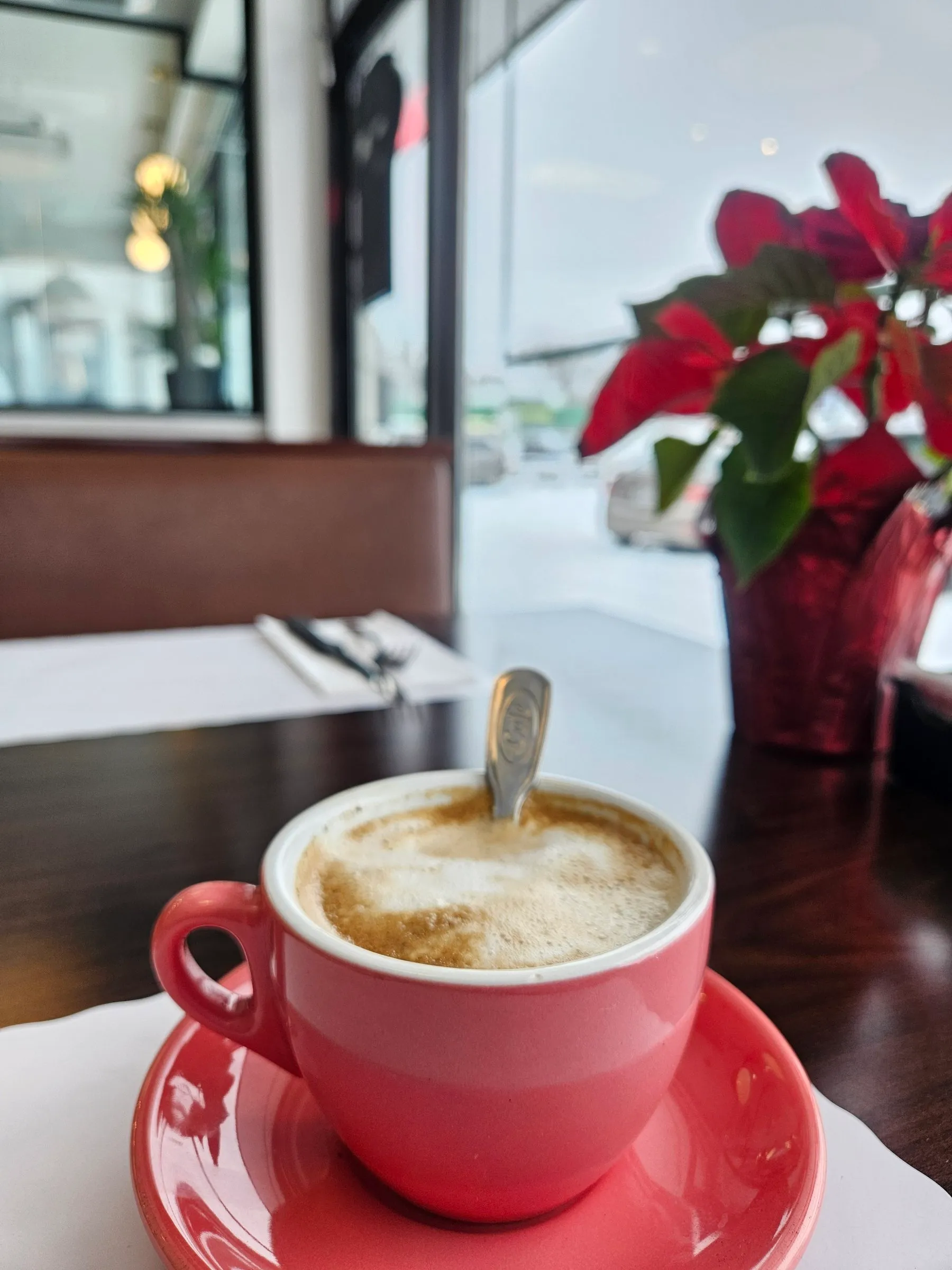Café mousseux dans une tasse rose, près d’un poinsettia