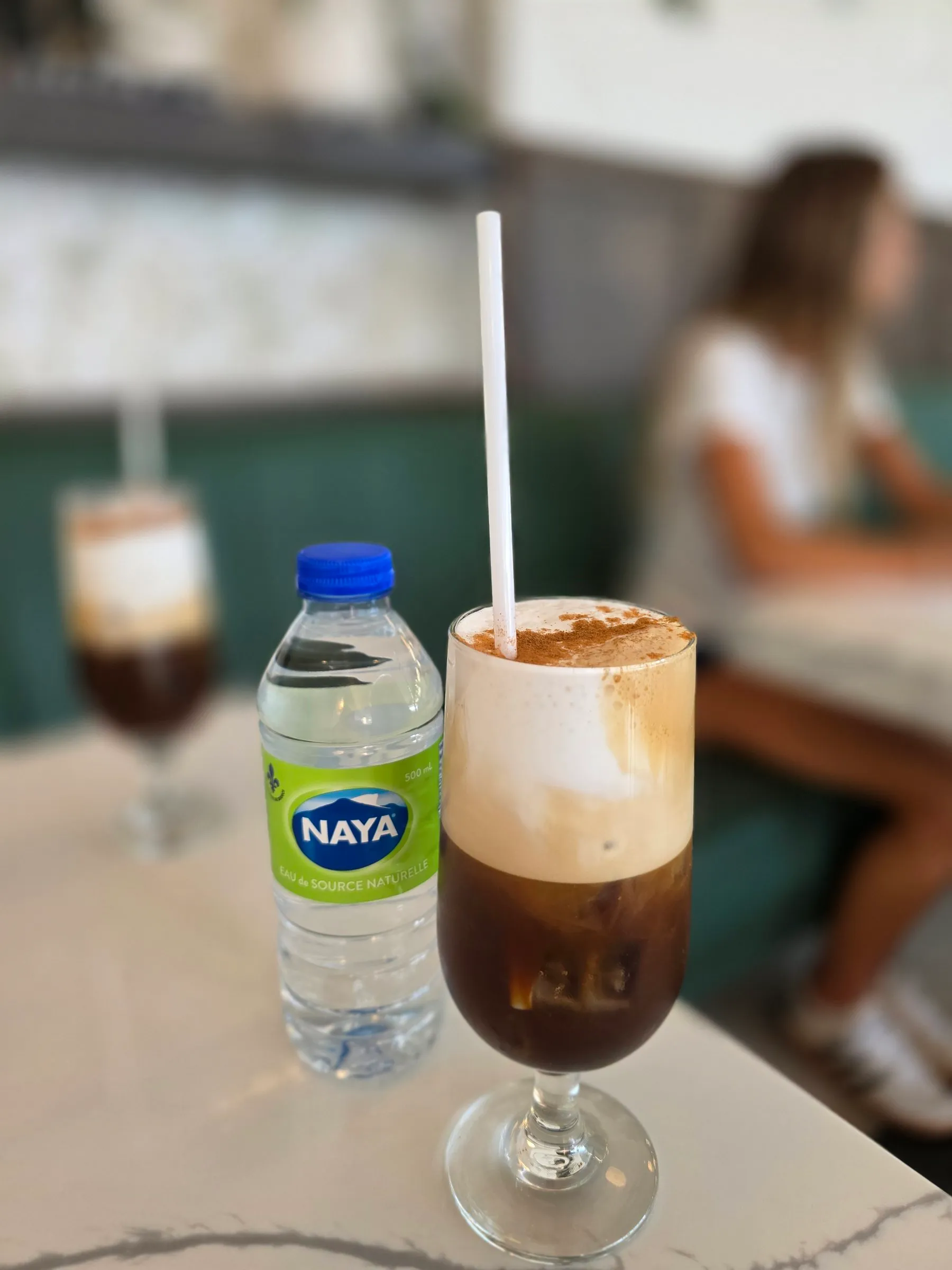 Café glacé avec mousse et paille sur une table de marbre