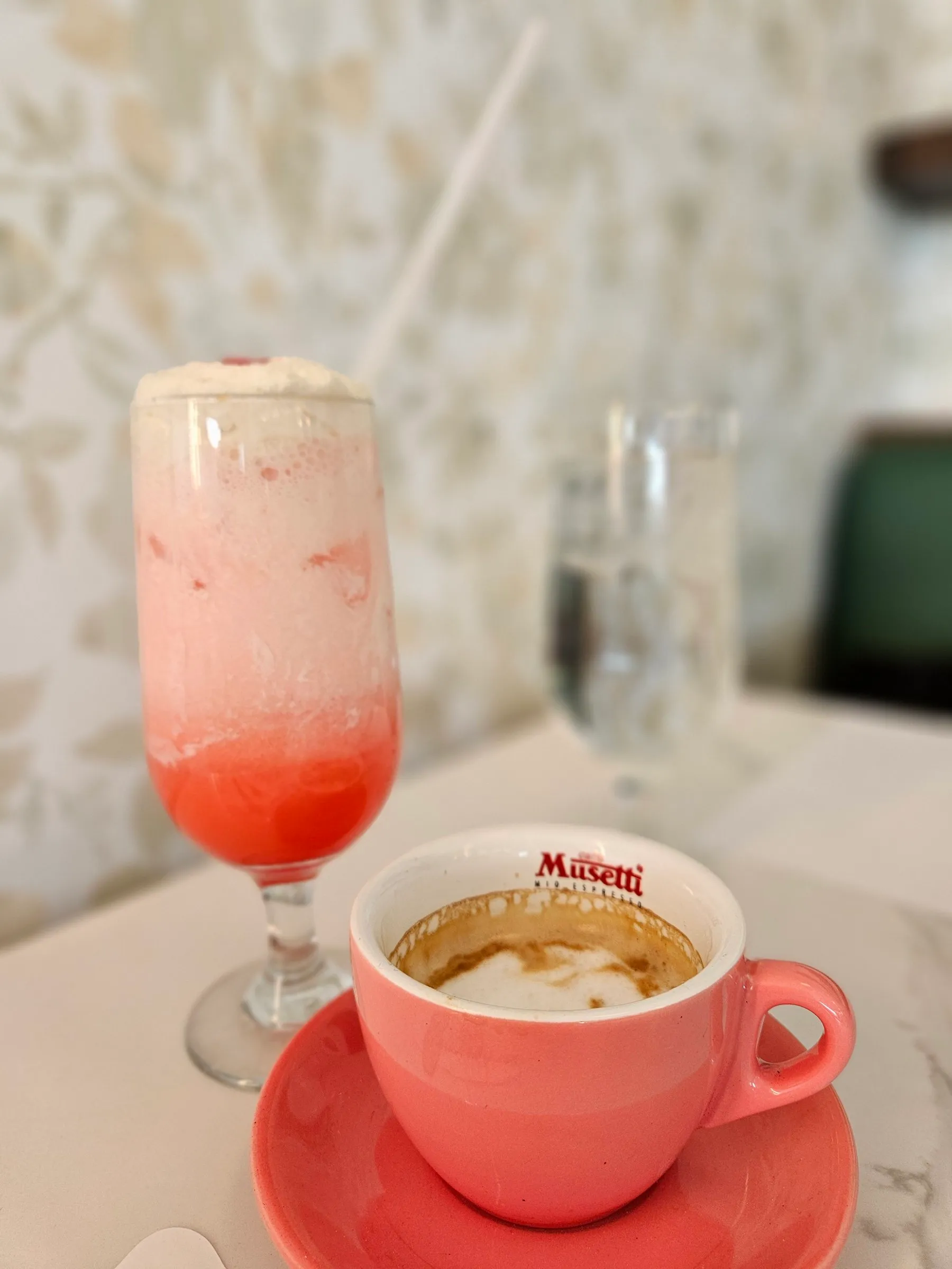 Café dans une tasse rose et boisson aux fruits sur une table de marbre