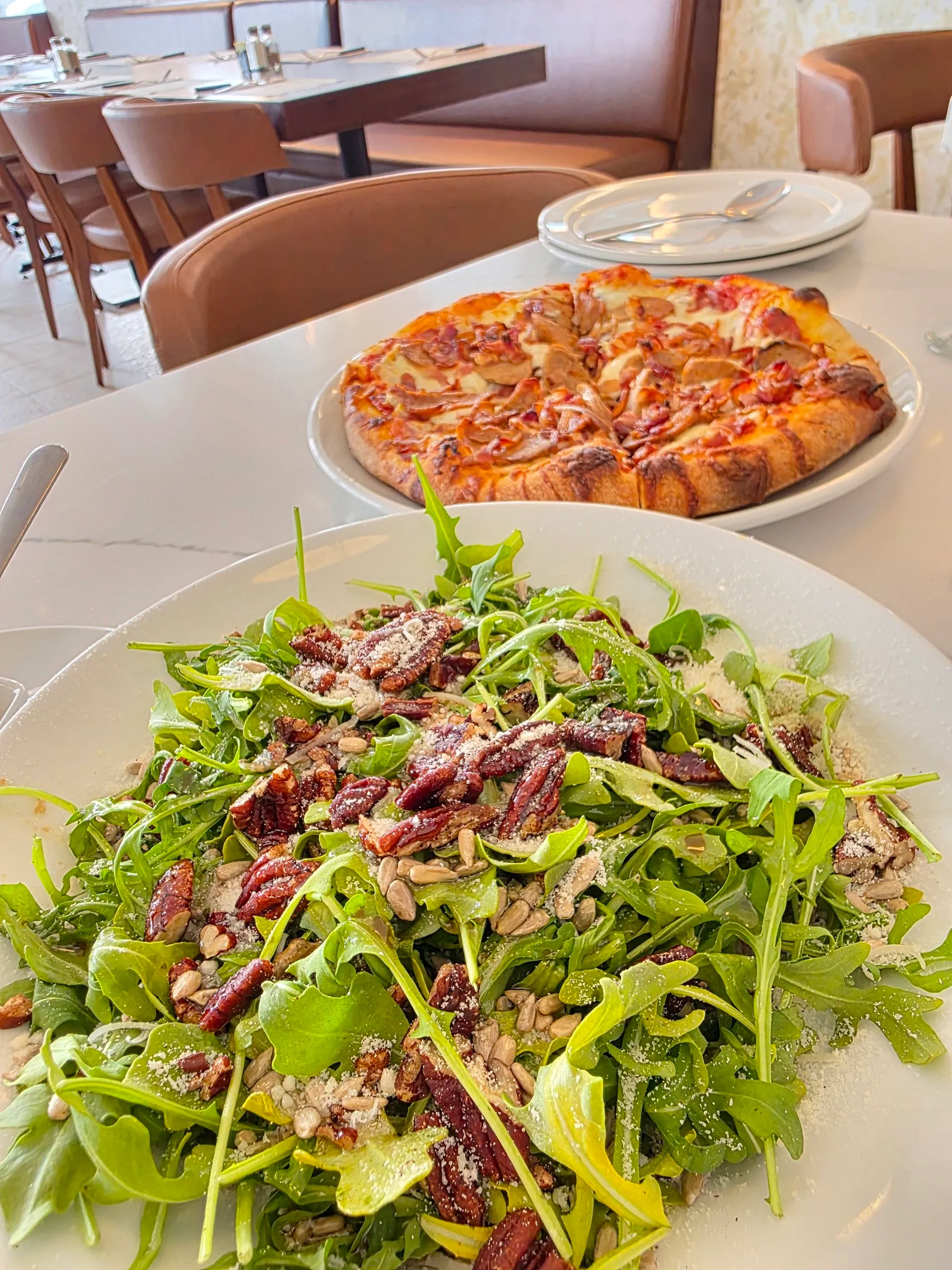 Pizza et salade de roquette aux noix sur une table