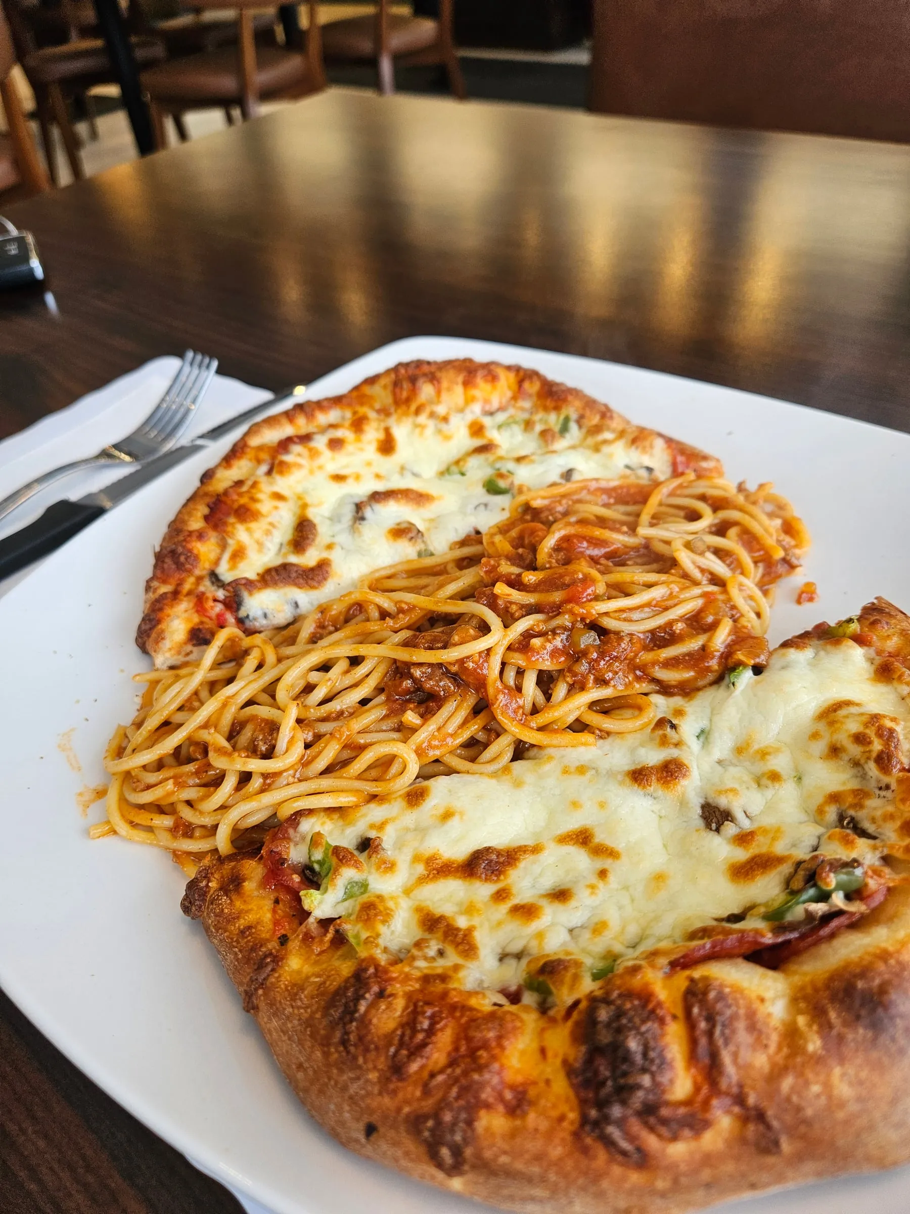 Pizza gratinée servie avec des spaghetti dans une assiette