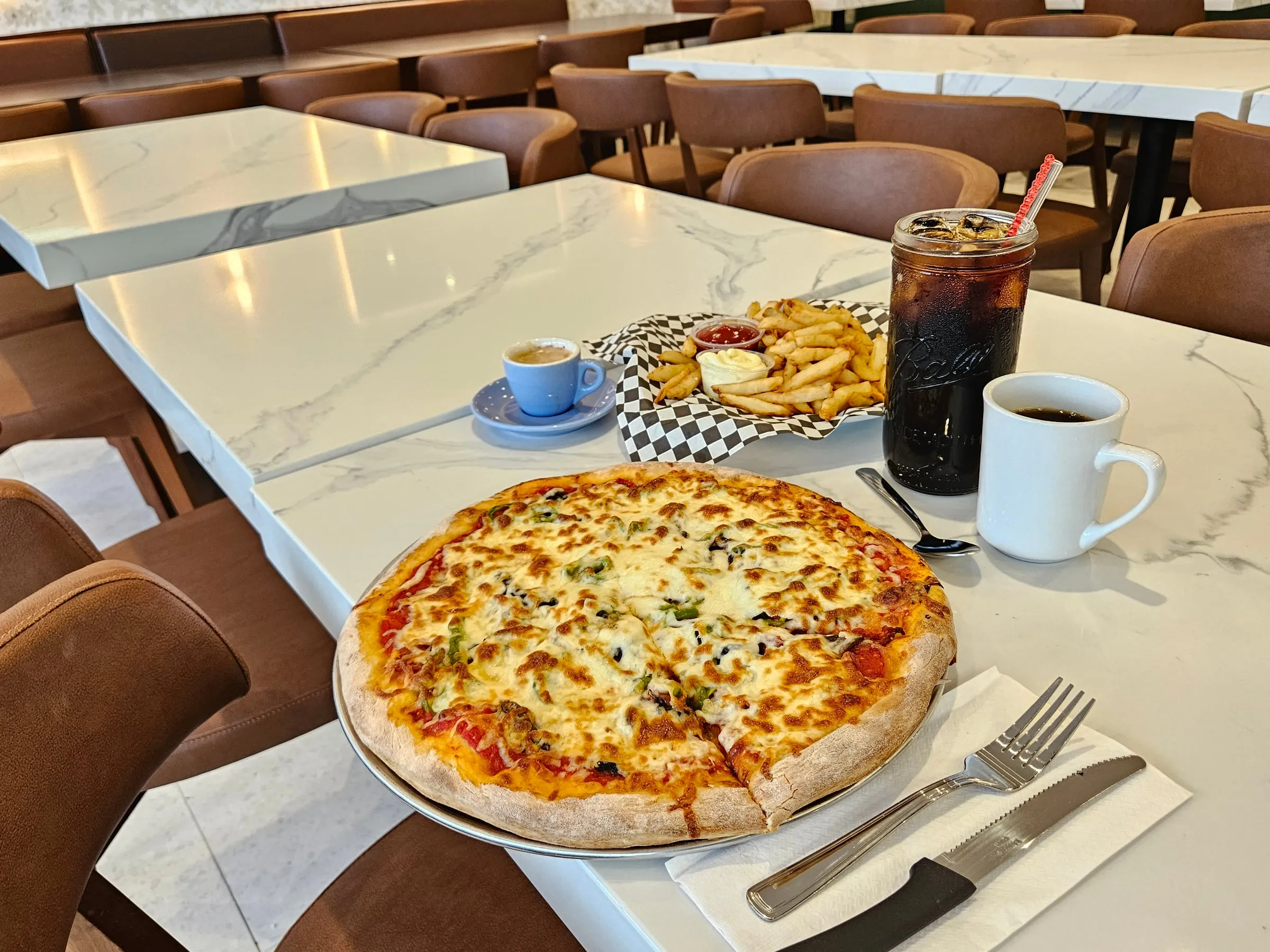 Pizza au fromage, frites et boissons sur une table de la salle à manger