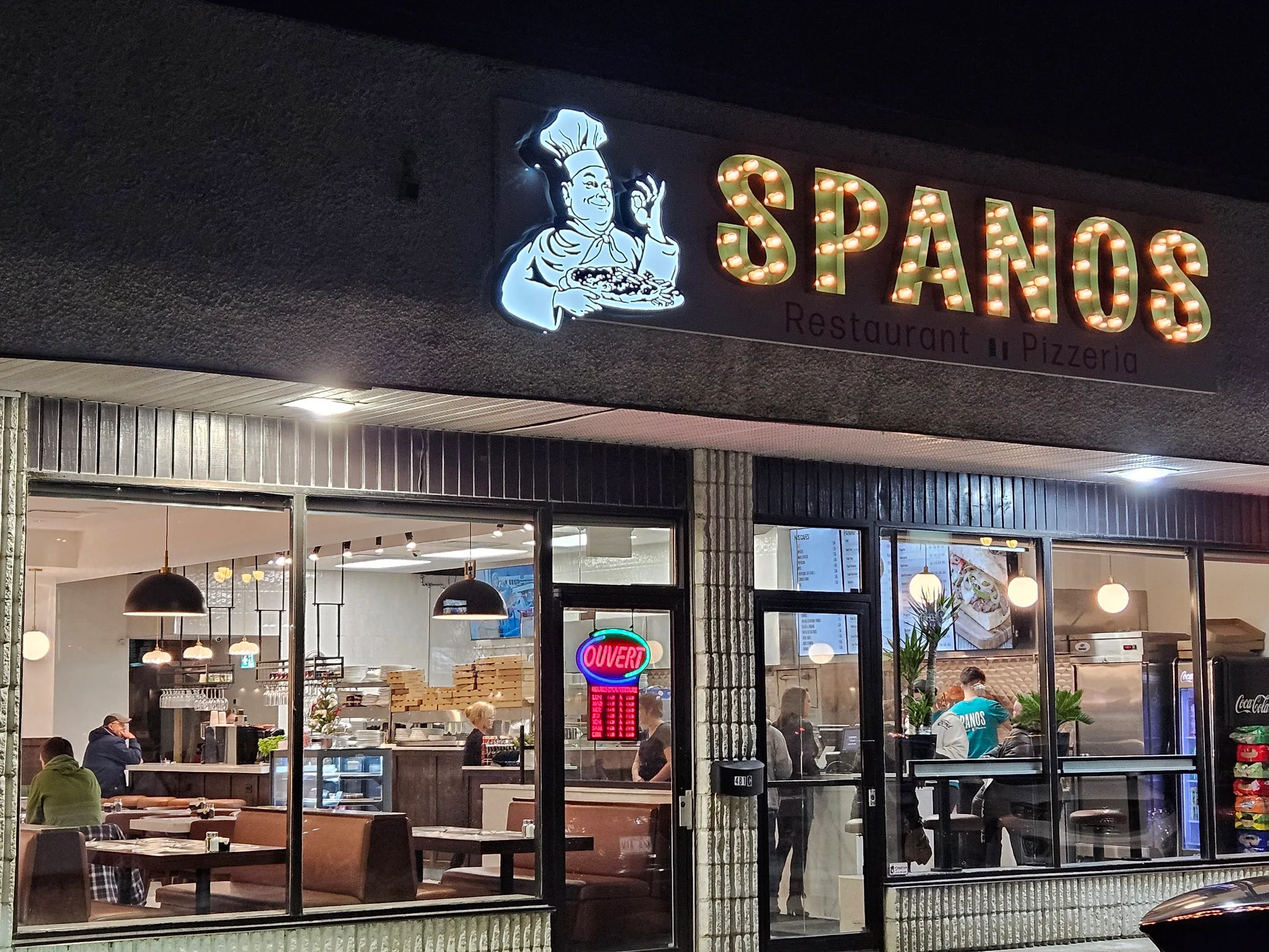 Façade et gigantesque enseigne Spanos éclairées la nuit