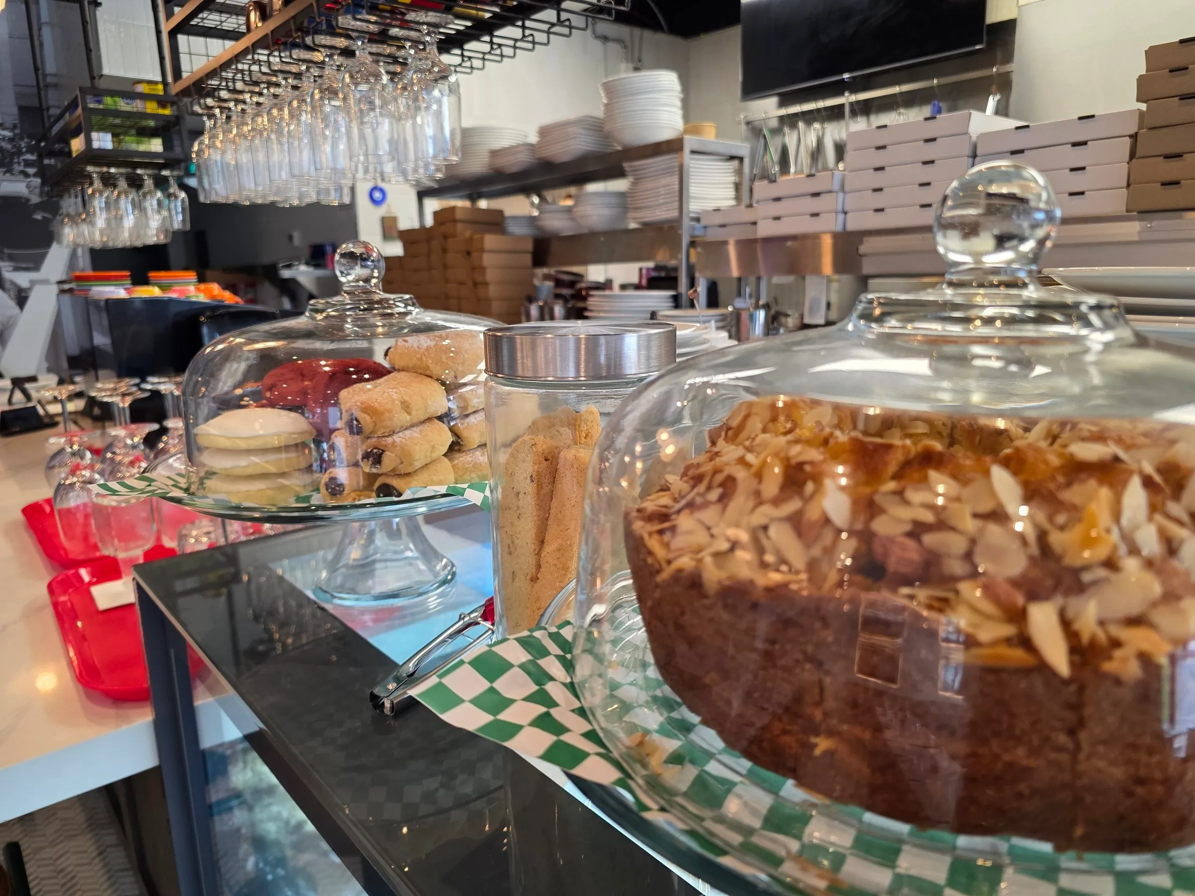 Gâteau garni d’amandes et pâtisseries sous cloche au comptoir