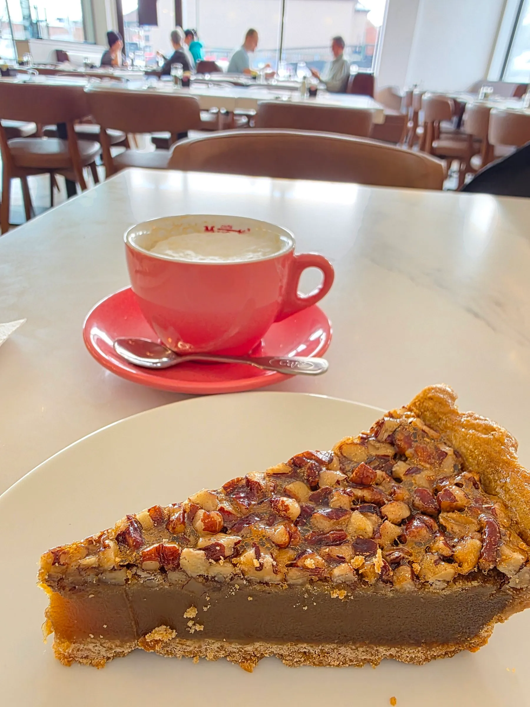Part de tarte aux pacanes accompagnée d’un café dans une tasse rose