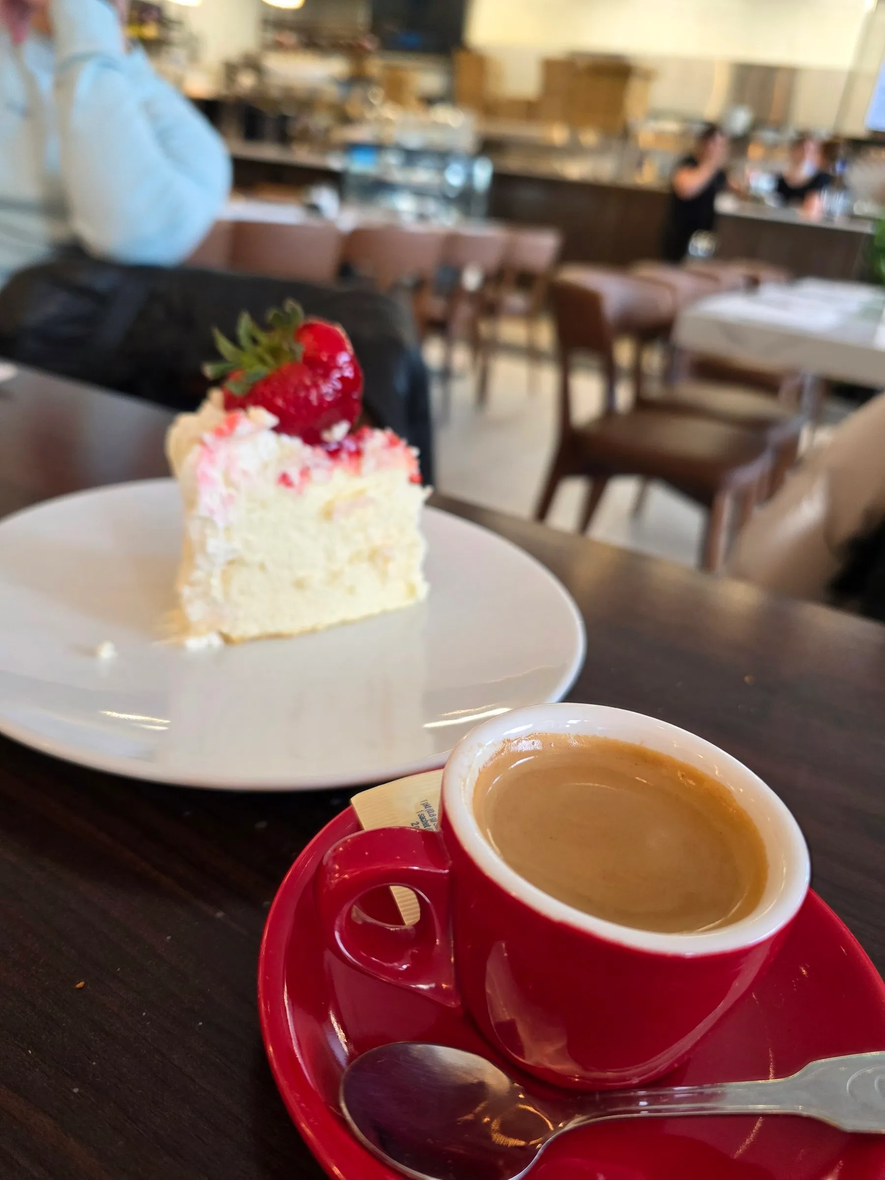 Part de gâteau au fromage garnie de fraises et tasse de café rouge