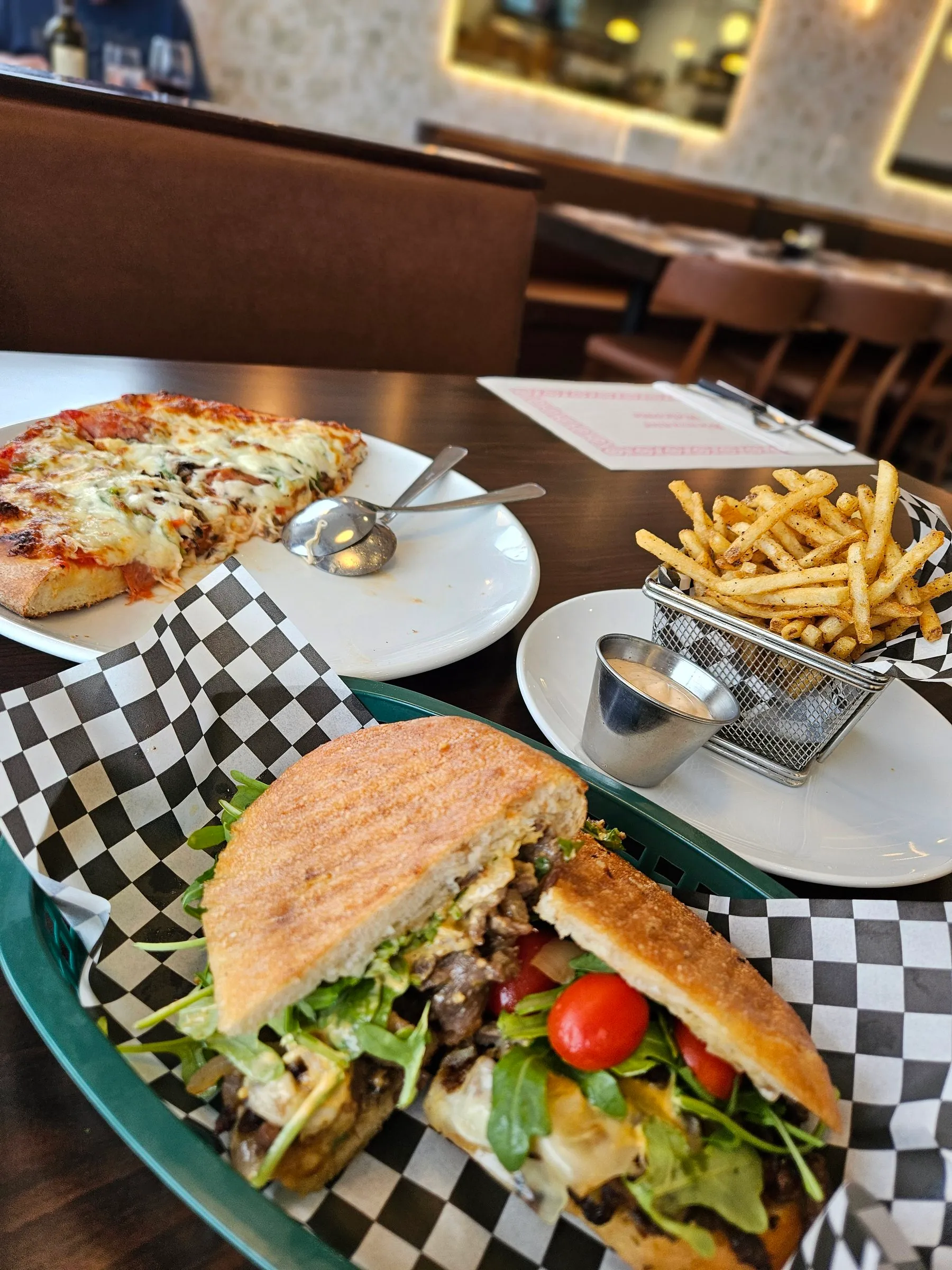 Pizza, panier de frites et sandwichs à partager sur une table